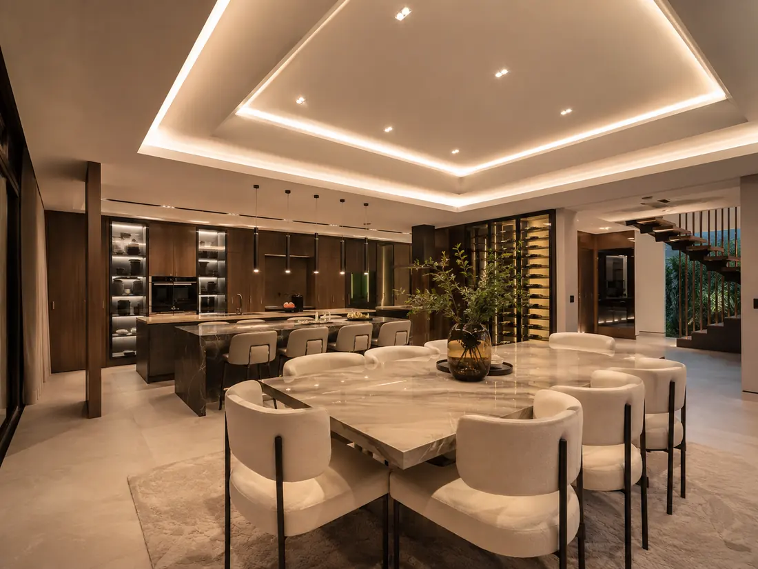 Comedor y cocina con mesa de mármol, techo con foseado de luz LED y bodega acristalada al fondo